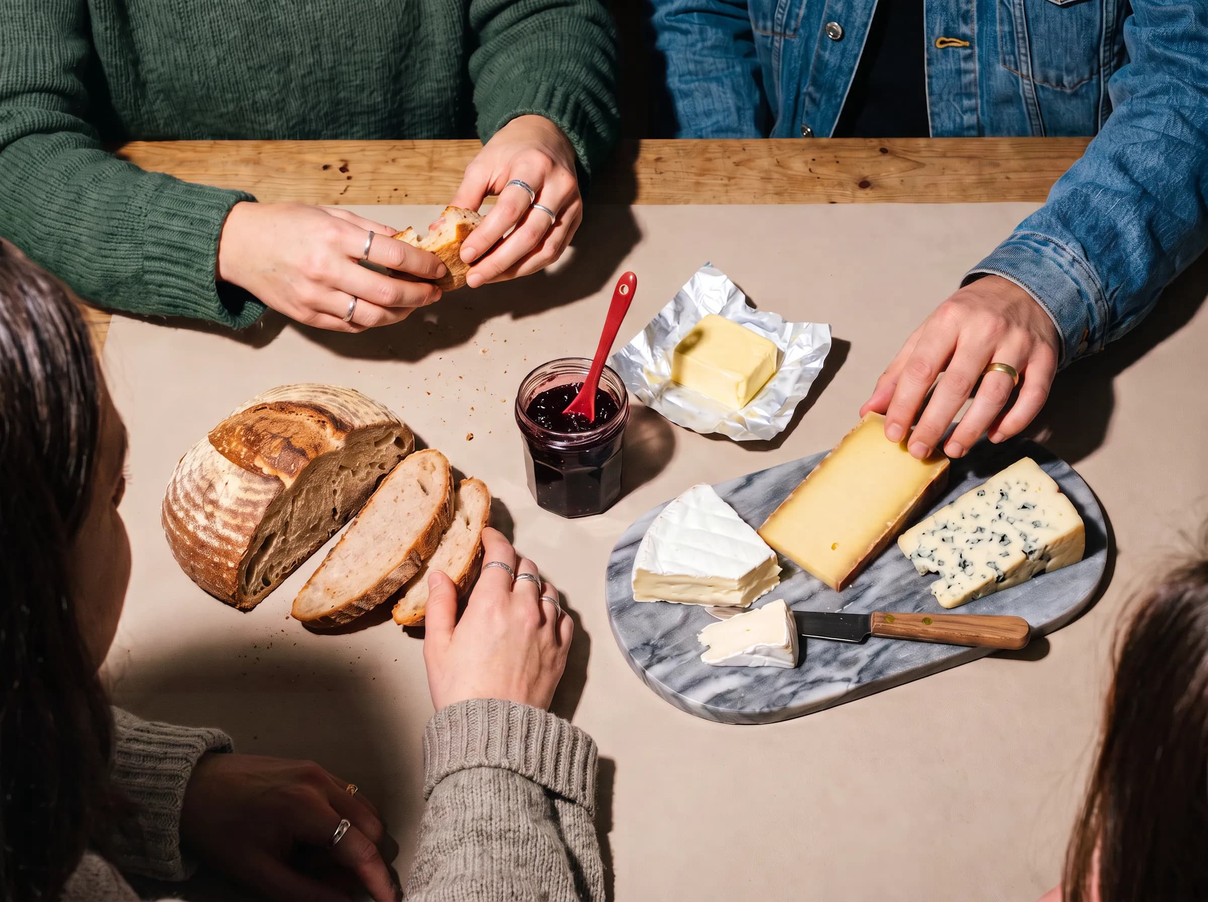 Quatre convives partagent du pain, du fromage et de la confiture autour d'une table